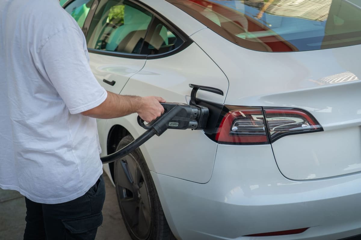 A driver plugging a Type 2 connector into an electric car at a workplace charging bay